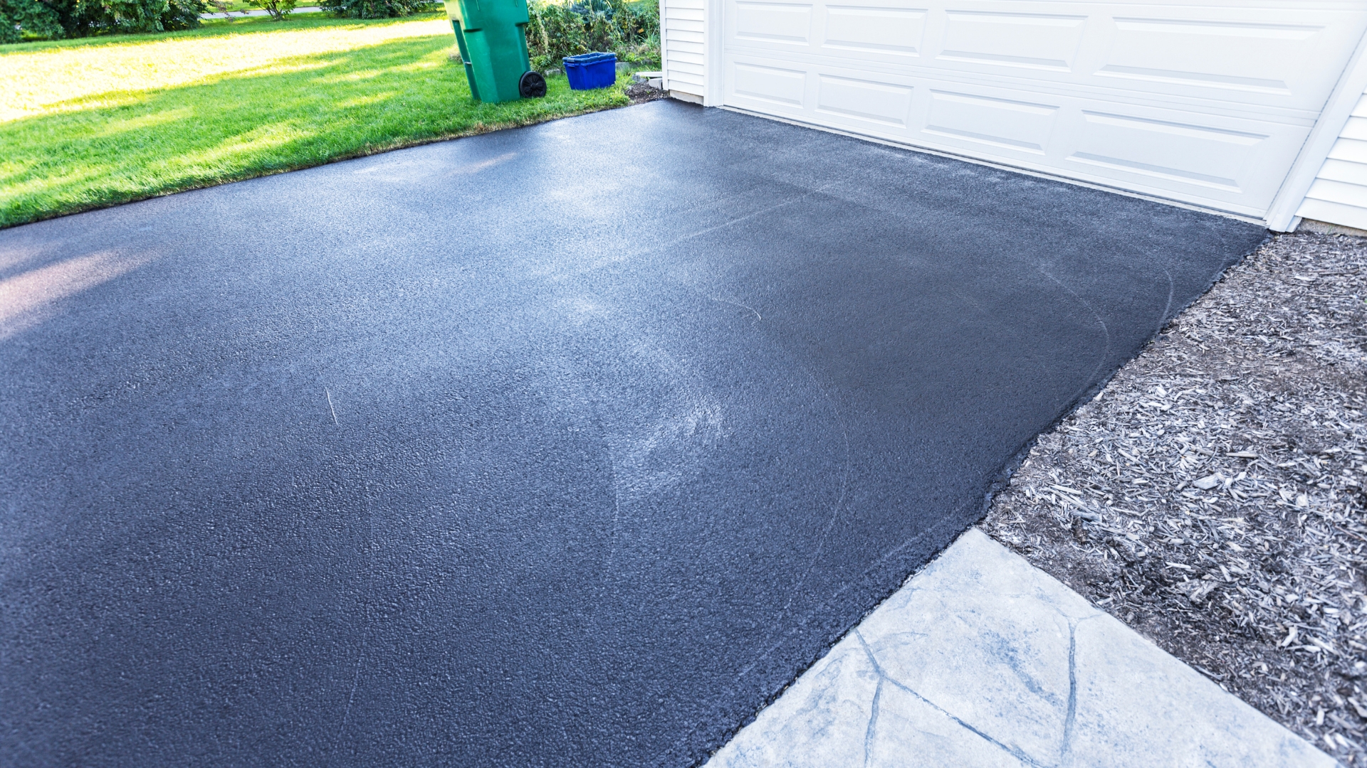 A garage with a black tarmac and a white garage door